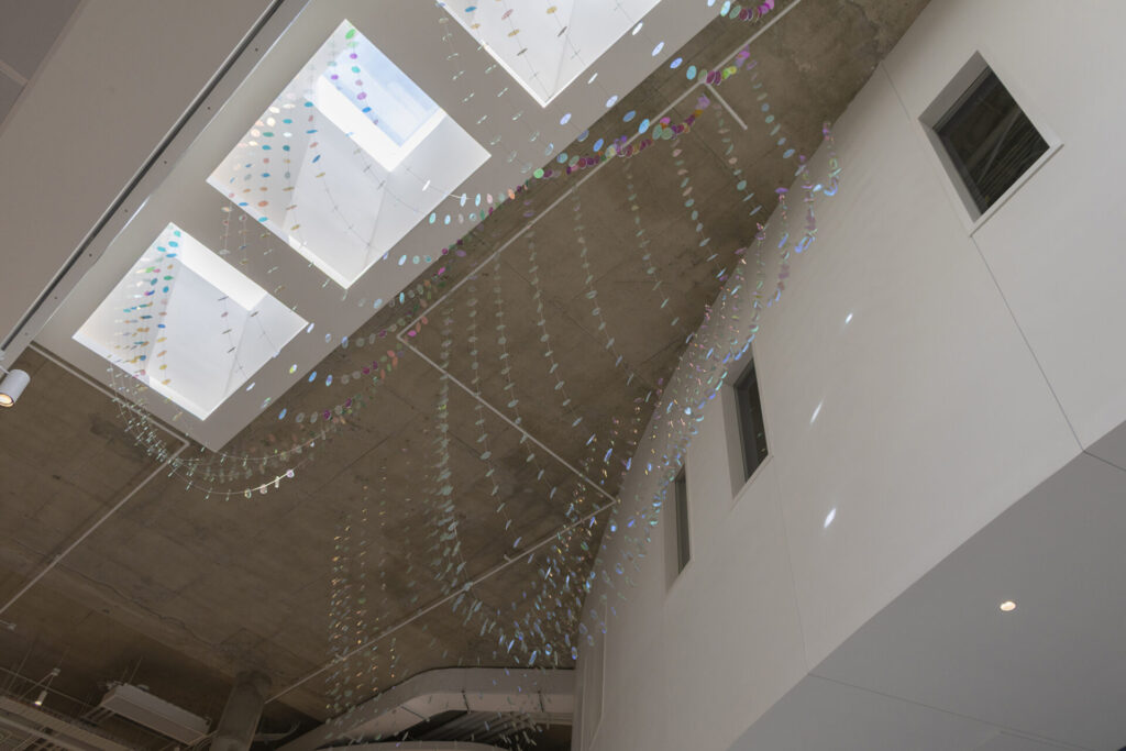 Looking up from the ground floor- Glass suspended sculpture with 2,000 dichroic glass flower petals and leaves appears to be more iridescent inside Steven Wymer Hall, University of Illinois Urbana-Champaign