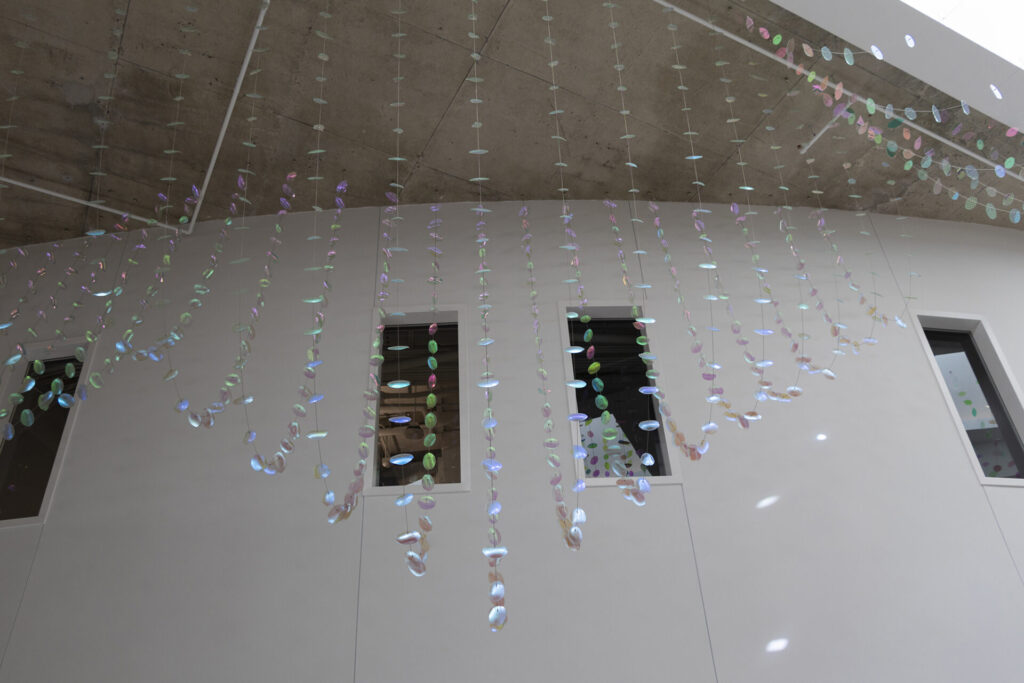 Detail view looking up from the ground floor- Glass suspended sculpture with 2,000 dichroic glass flower petals and leaves appears to be more iridescent inside Steven Wymer Hall, University of Illinois Urbana-Champaign