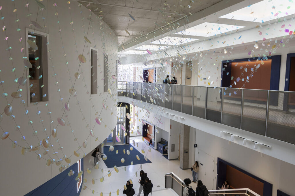 Between the classes, the students are passing through the atrium of Wymer Hall, University of Illinois Urbana-Champaign, under the glass suspended sculpture
